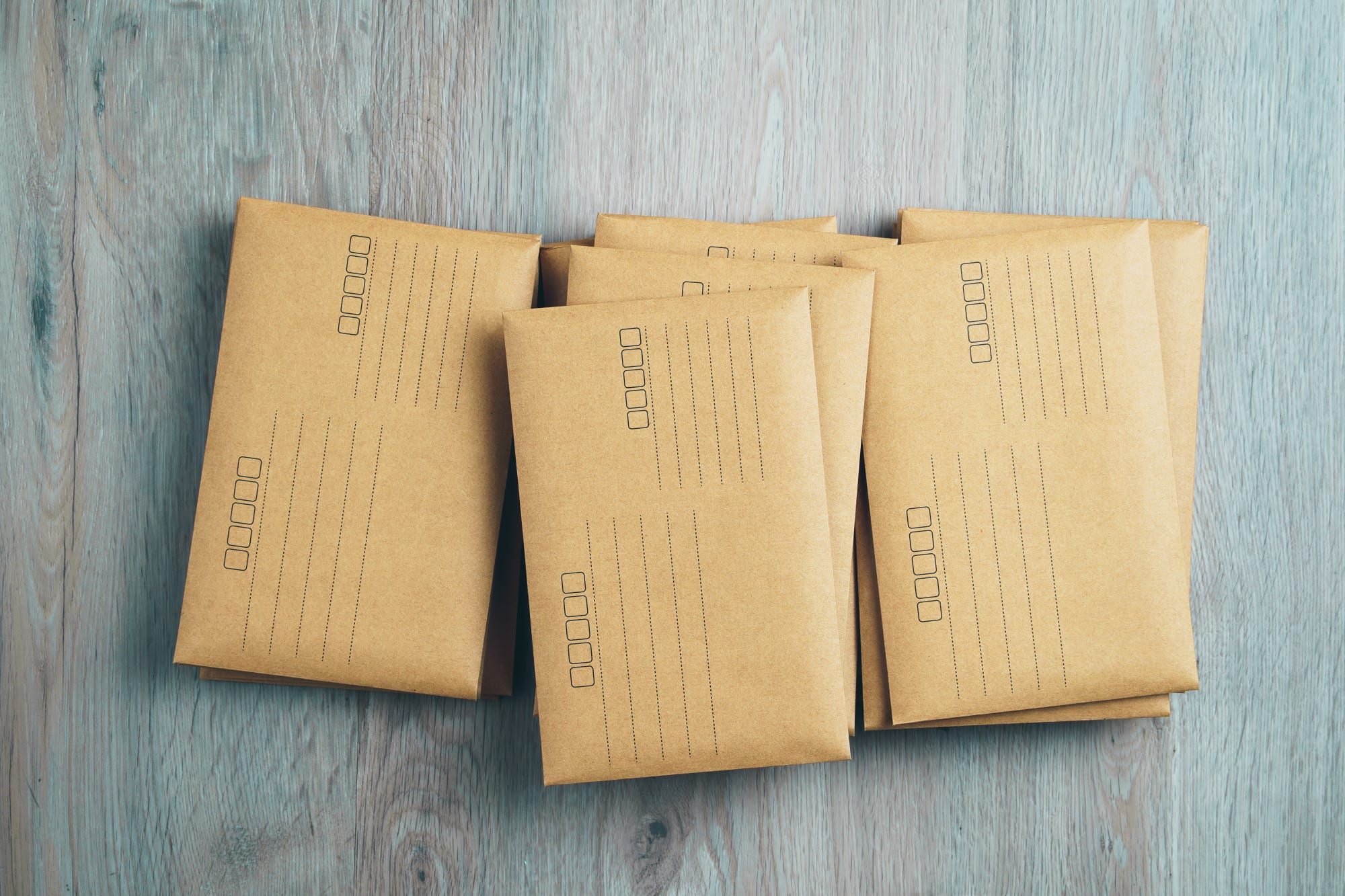 Stacked brown envelopes on wooden background.